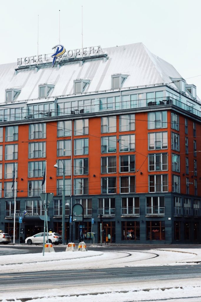 A snowy scene of Hotel Opera in Gothenburg, Sweden, showcasing its unique architecture.